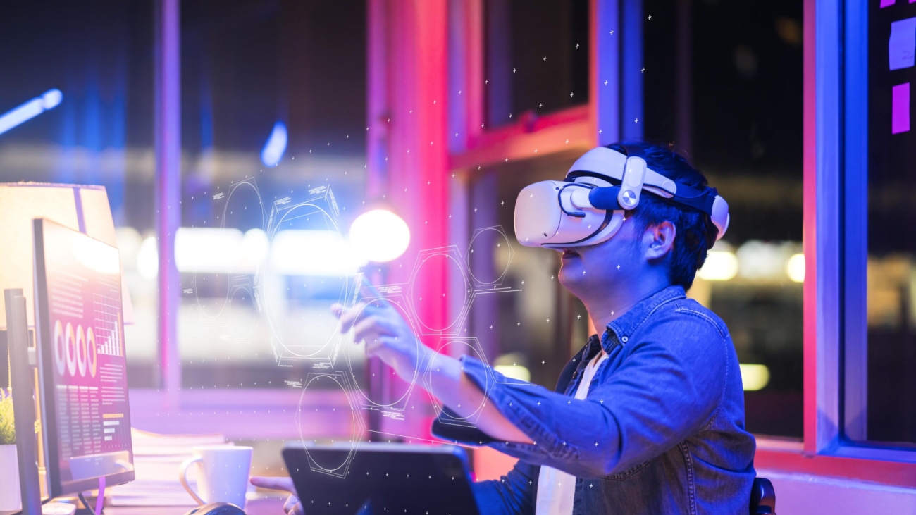 asian-young-male-wearing-wearable-goggle-headset-virtual-online-meeting-digital-space-working-with-3d-augmented-dimension-homecyber-virtual-working-with-virtual-vr-goggle-pc-desktop-device-min